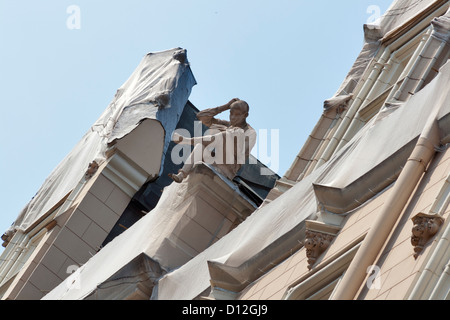 Statue d'un garçon de la lecture d'un livre, au-dessus du bâtiment à Riga, Lettonie. Banque D'Images