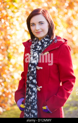 Jeune femme portant un manteau rouge dans un parc en Ecosse. Banque D'Images