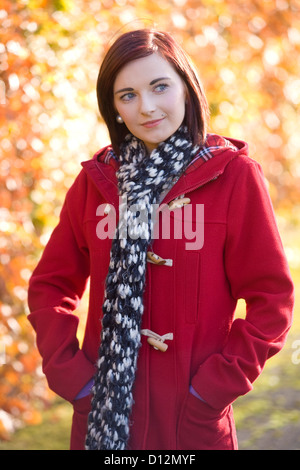 Jeune femme portant un manteau rouge dans un parc en Ecosse. Banque D'Images