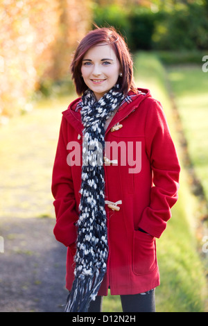 Jeune femme portant un manteau rouge dans un parc en Ecosse. Banque D'Images