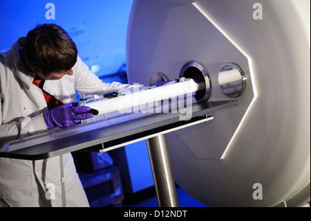 Technicien scientifique ou charge un spécimen sur un plateau dans un petit orifice de l'imagerie par résonance magnétique (IRM) Banque D'Images