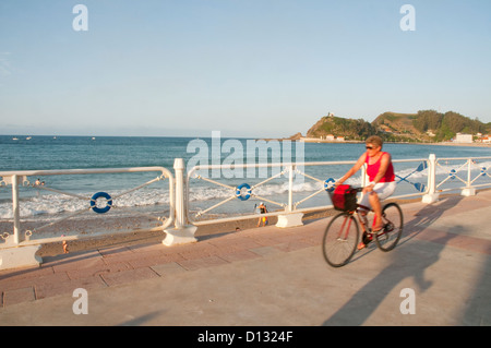 Mature Woman riding en vélo le long de la promenade. Santa Marina beach, Ribadesella, Asturies, Espagne. Banque D'Images