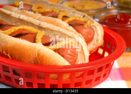 Deux hot-dogs grillés fraîchement dans un panier avec des condiments Banque D'Images