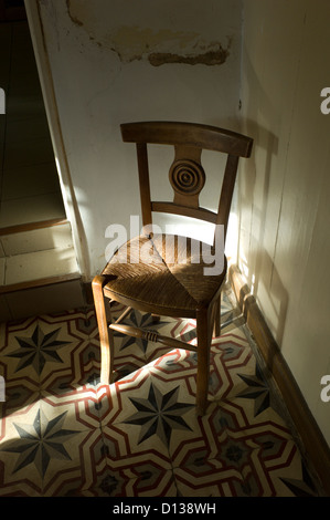 Wicker Chair dans la lumière du soleil sur le carrelage à motifs Banque D'Images