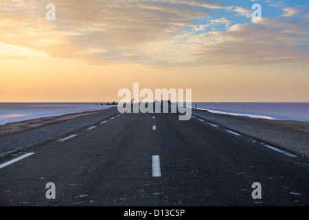 Large route asphaltée jusqu'à la frontière avec l'Algérie, de la Tunisie à l'aube à travers le lac salé chott El Jerid, Tunisie, Afrique Banque D'Images