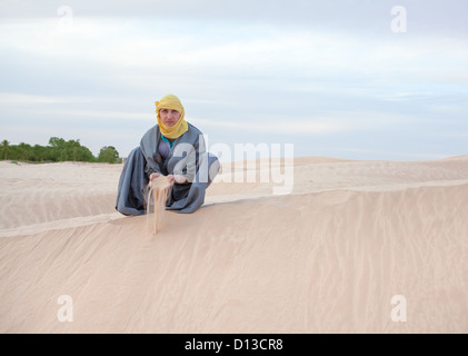 Man dans l'est de la protection de la coulée en sable vêtements mains sur desert dune. Copy space Banque D'Images