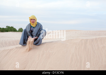 Personne de race blanche dans l'est de la protection de la coulée en sable vêtements mains sur desert dune. Copy space Banque D'Images