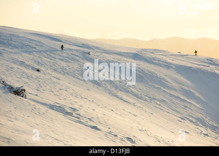 Les promeneurs sur Helvellyn dans la neige, Lake District, UK, au coucher du soleil. Banque D'Images