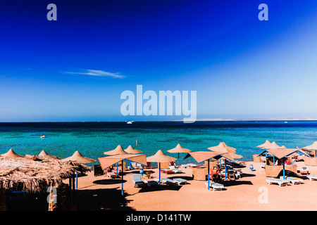 Parasols et chaises longues sur une plage privée dans la station balnéaire d'Hurghada. Mer Rouge, Egypte Banque D'Images