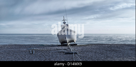 Un seul bateau de pêche en la lumière froide sur un matin d'hiver glacial à Dungeness, Kent Banque D'Images