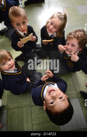 Un écolier eating toast après matin Assemblée générale à Notre Dame et St Werburgh's Catholic Primary School à Newcastle-under-Lyme, St Banque D'Images