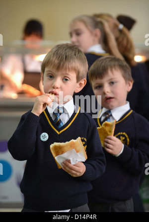 Un écolier eating toast après matin Assemblée générale à Notre Dame et St Werburgh's Catholic Primary School à Newcastle-under-Lyme, St Banque D'Images