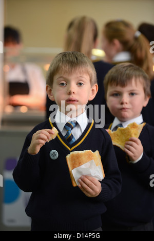 Un écolier eating toast après matin Assemblée générale à Notre Dame et St Werburgh's Catholic Primary School à Newcastle-under-Lyme, St Banque D'Images