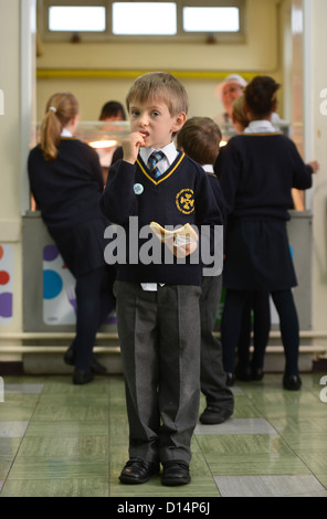 Un écolier eating toast après matin Assemblée générale à Notre Dame et St Werburgh's Catholic Primary School à Newcastle-under-Lyme, St Banque D'Images