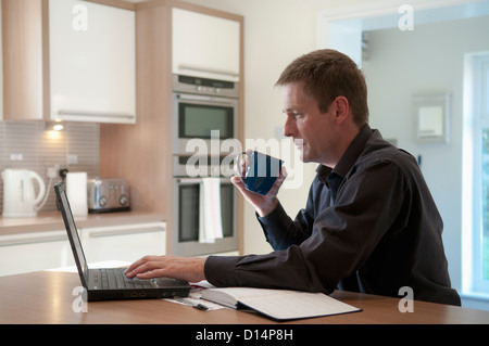 Businessman working on laptop in kitchen Banque D'Images