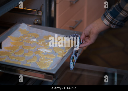 La main de l'enfant met les matières les biscuits de Noël au four Banque D'Images
