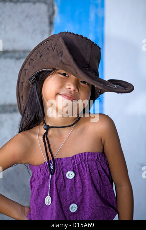 Un mignon, jeune fille Philippine modèles un chapeau de cuir marron, et une robe pourpre aux Philippines. Banque D'Images