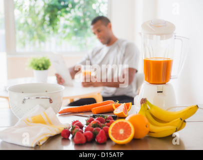 USA, New Jersey, Jersey City, jeune homme assis dans la cuisine et boire du jus Banque D'Images