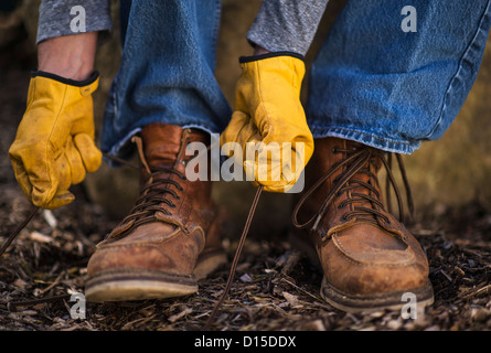 USA, New Jersey, Mendham, homme attachant chaussures dans gants de protection Banque D'Images