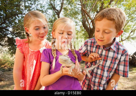 USA, Utah, Léhi, trois enfants (4-5, 6-7) heureux d'être à la recherche à lizard étant détenu par enfant au milieu Banque D'Images