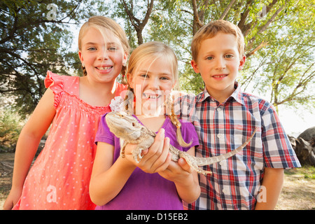 USA, Utah, Léhi, trois enfants (4-5, 6-7) heureux d'être à la recherche à lizard étant détenu par enfant au milieu Banque D'Images