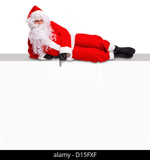 Santa Claus située au-dessus d'un panneau d'affichage vierge pointant sur une zone blanche vide où vous pouvez ajouter votre propre texte. Banque D'Images