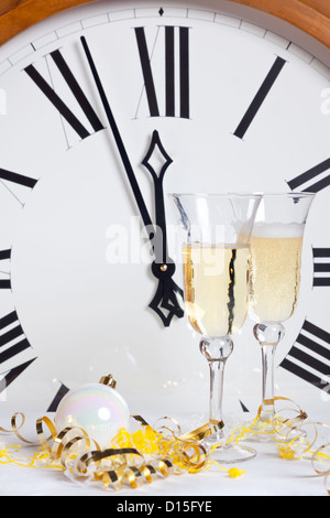 A propos de grève minuit le Nouvel An avec des verres de champagne et des serpentins en face d'une grande horloge. Banque D'Images