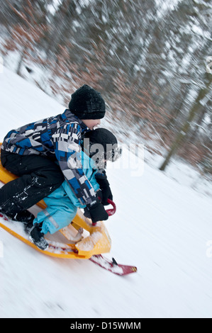 Deux jeunes garçons allant en descente sur un traîneau neige moderne Banque D'Images