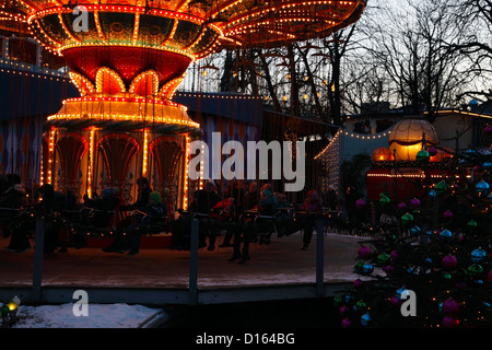 Le carrousel de rotation, les arbres de Noël et des décorations au crépuscule au marché de Noël de la neige recouvrait les jardins de Tivoli, Copenhague, Danemark Banque D'Images