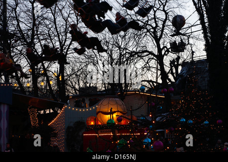 Silhoueté des gens au crépuscule dans le carrousel à balançoires ou le chairoplane dans le Tivoli décoré de Noël, Copenhague, Danemark Banque D'Images