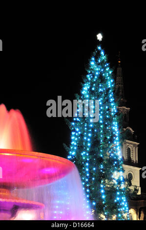 Trafalgar Square London UK 8-12-2012 Le maire de Londres a salué le gamesmakers, Équipe paris billet d'ambassadeurs qui n'ont leur bit lors d'un concert de chants de Noël en leur honneur à Trafalgar Square, le centre de Londres ce soir.Team London's 'couleurs' Olympique de violet et magenta se reflétaient dans les fontaines eclairage pour l'occasion . Derrière, l'arbre de Noël allumé récemment, a fait don à la population de Londres par la ville d'Oslo chaque année depuis 1947 et l'emblématique de Londres monument ,St Martin-in-the-Fields Anglican Church spire. Banque D'Images