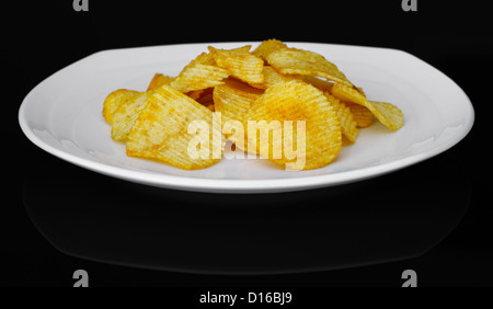 Croustilles de pommes de terre sur une plaque sur fond noir Banque D'Images