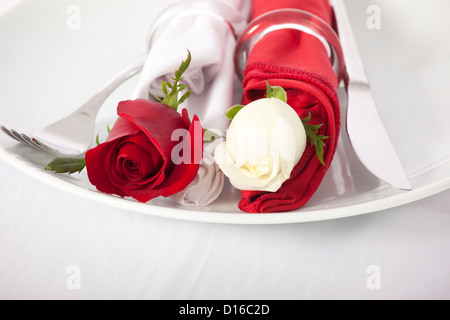 Libre de rouge et rose blanche et couverts on white plate Banque D'Images