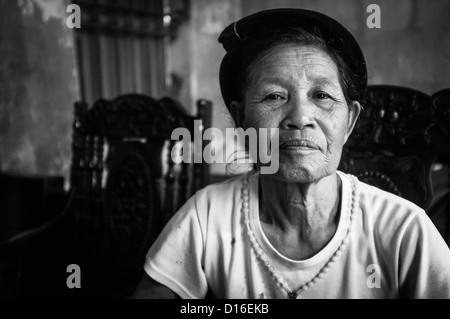 Image en noir et blanc d'une vieille femme vietnamienne dans un t-shirt blanc et un chapeau noir Banque D'Images