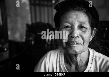 Image en noir et blanc d'une vieille femme vietnamienne dans un t-shirt blanc et un chapeau noir Banque D'Images