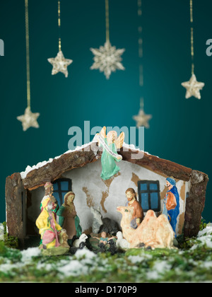 Libre de naissance de l'enfant Jésus scène avec des figurines de bois, la neige et les étoiles sur fond bleu Banque D'Images