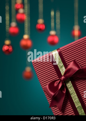 Gros plan du bourgogne unique boîte cadeau carton encadrée dans le coin inférieur droit de l'image avec des décorations de Noël rouge sur fond bleu Banque D'Images