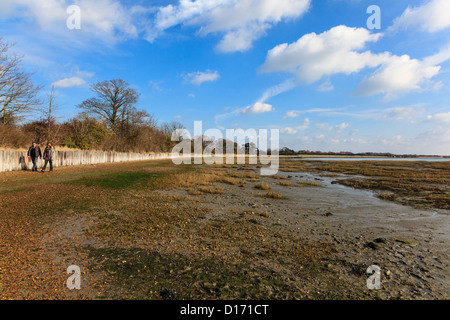 Homme et femme marche sur le Solent Way sentier sur la plage du Port de Langstone, Hampshire, Royaume-Uni Banque D'Images