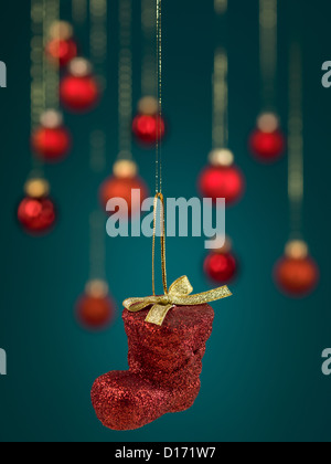 Gros plan du cuir rouge de noël suspendus décoration d'amorçage de l'arc, avec des fils d'or sur fond dégradé bleu rouge brouillée avec globes Banque D'Images