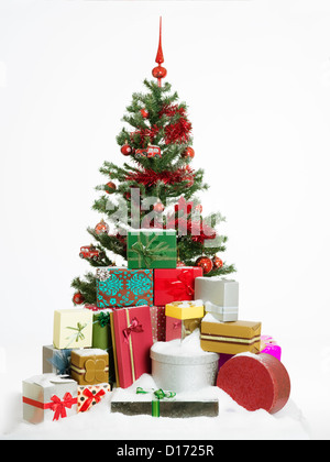 Arbre de Noël décoré magnifiquement entouré par un tas de cadeaux colorés couverts de neige, isolé sur fond blanc Banque D'Images