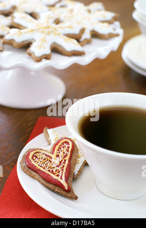 Heart shaped gingerbread cookie, décorée pour Noël, et une tasse de café. Banque D'Images