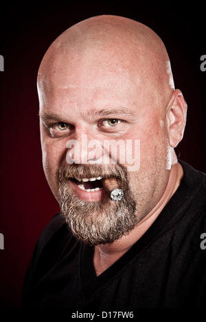 Homme chauve avec une barbe fume un cigare Banque D'Images