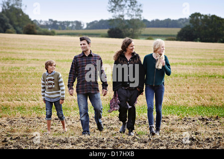 Family walking together in grassy field Banque D'Images