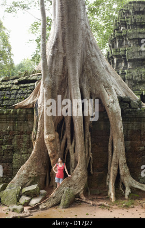 Femme debout par des racines d'arbre géant Banque D'Images