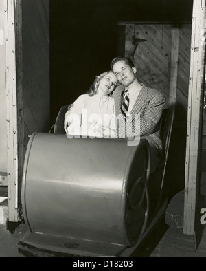 Lovesick teenage couple sitting in carnival ride, années 1950, 1960 Banque D'Images