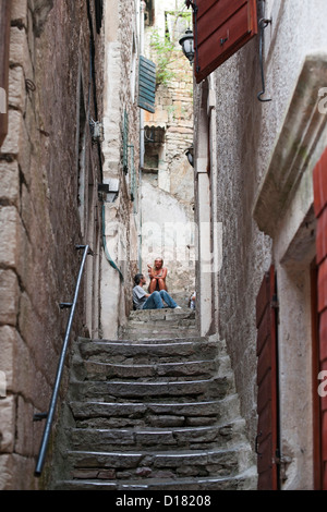 Des gens assis sur un escalier en pierre dans la vieille ville de Kotor au Monténégro. Banque D'Images