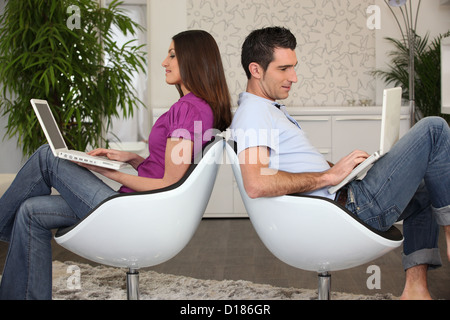 L'homme et la femme assis dos à dos à l'aide d'ordinateurs Banque D'Images