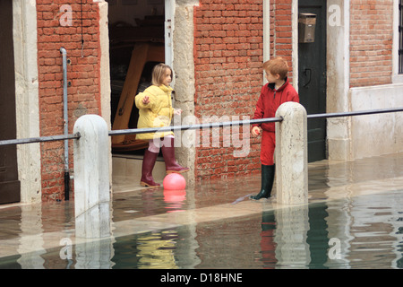 Enfants jouant dans la rue au cours de "acqua alta" Inondations à Venise. Banque D'Images