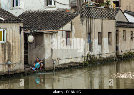 Vêtements femme âgée se lave le long du canal Shantang à Suzhou, Chine. Banque D'Images