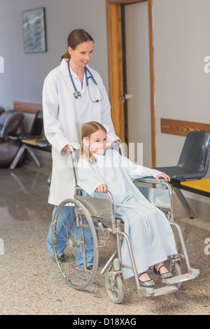 Docteur wheeling un patient dans un fauteuil roulant Banque D'Images